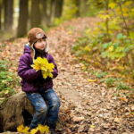 Bambino nel bosco in autunno con foglie