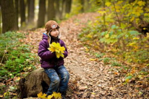 Bambino nel bosco in autunno con foglie